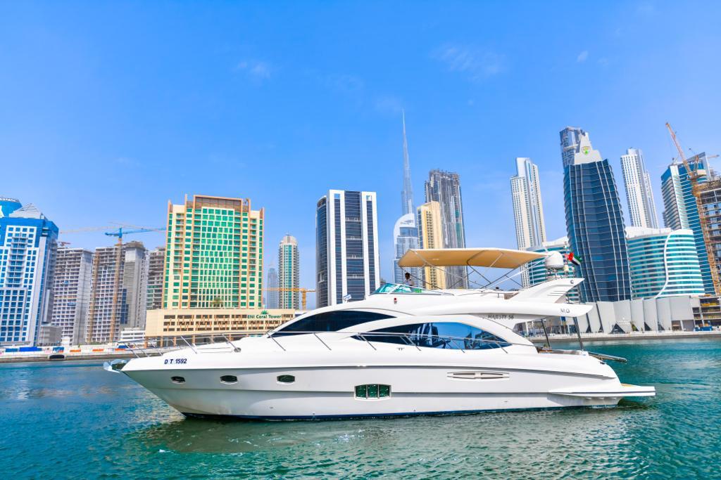A white luxury yacht is docked in a body of water with Marina skyscrapers
