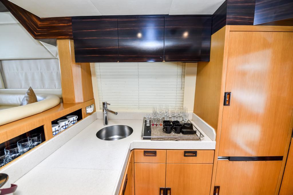 A kitchen in Luxury yacht on rent in Dubai with wooden cabinets and a sink.